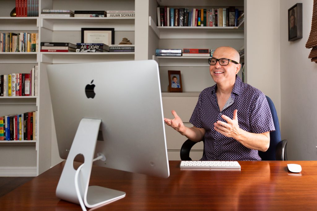 Alan Watt sitting in his office at his computer on a zoom online writing workshop coaching writers, books behind him