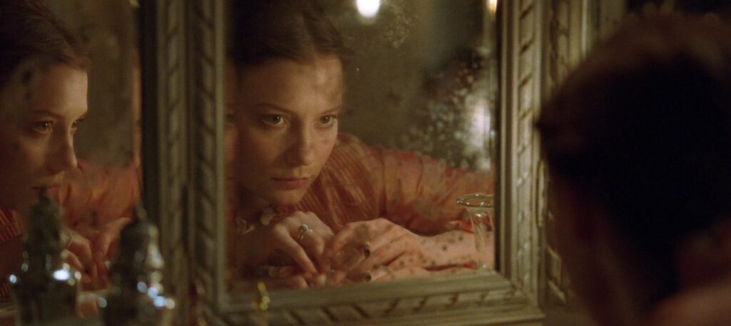 Image of a woman looking into an old multi-panel mirror from Madame Bovary film.