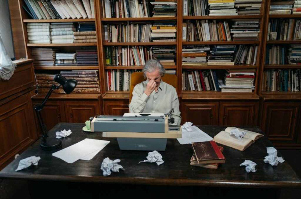 writer’s block - Image of a frustrated male writer with a typewriter and crumpled papers on the desk.