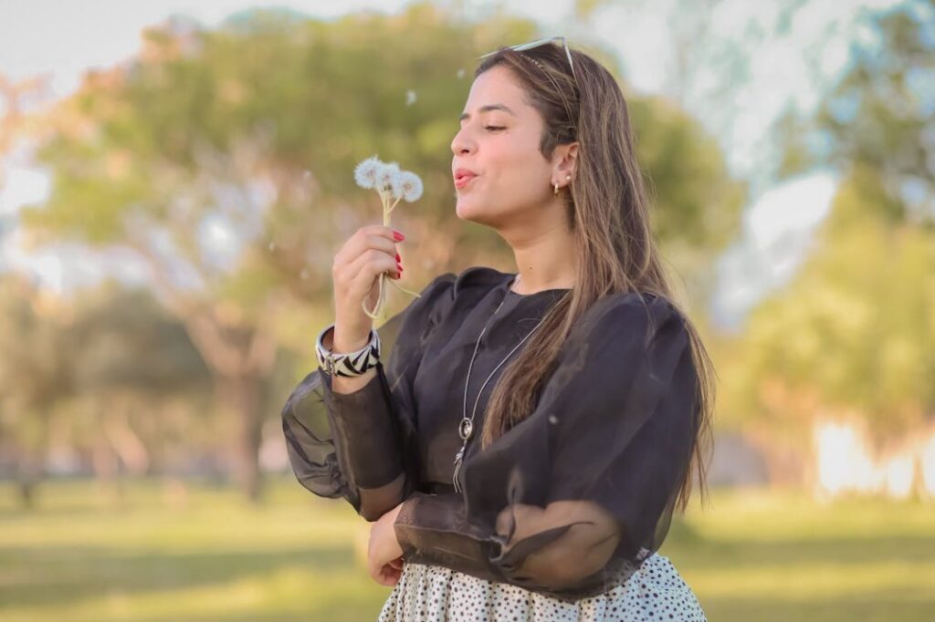 Woman blowing on dandelions, making wishes. 