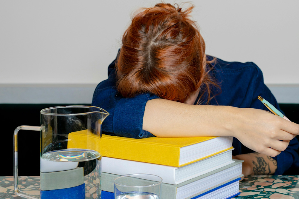 Pantser struggling to write by the seat of their pants, head rested on books.