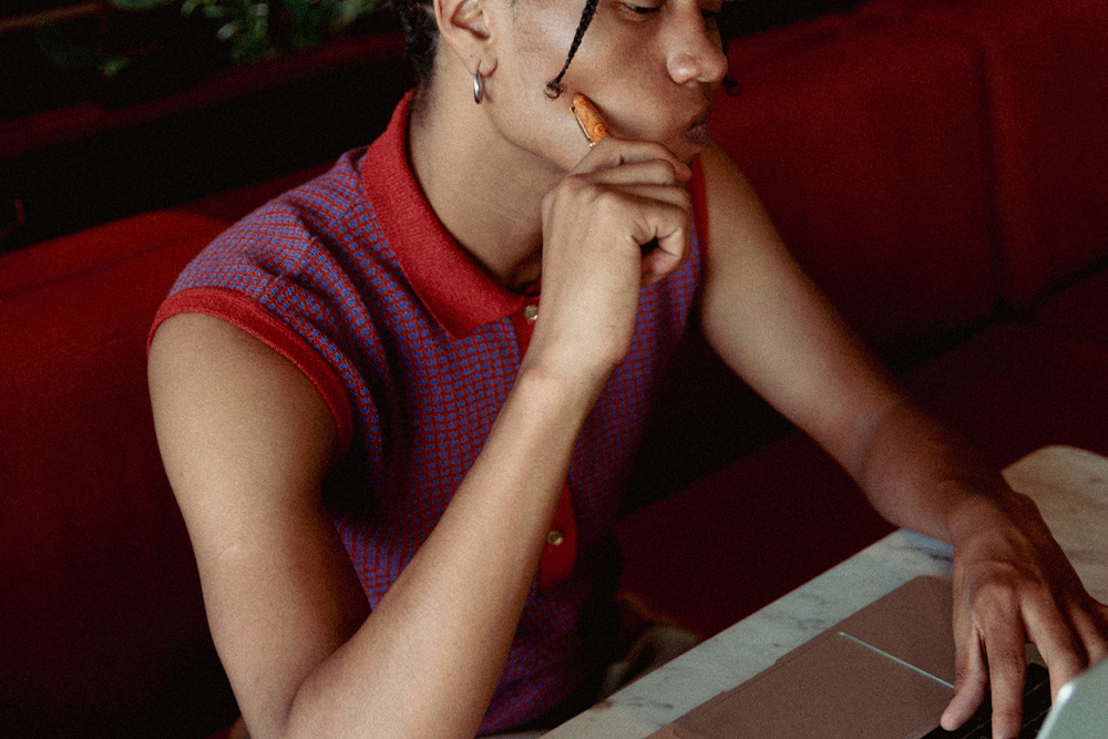 Woman thinking in front of her laptop to depict "before drafting" thought processes on character profiles