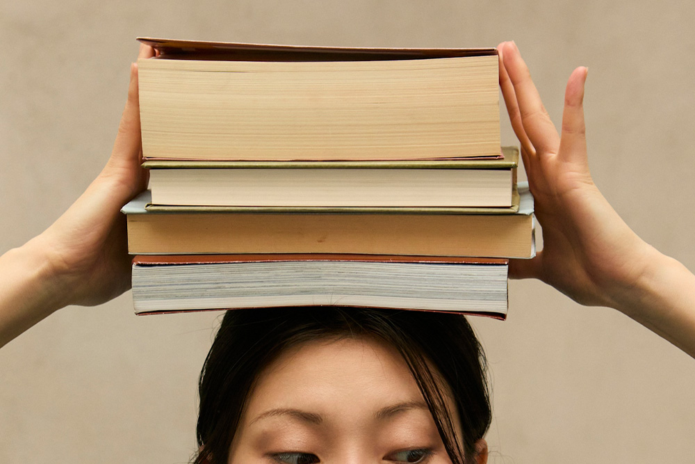 Balancing an idea on one's head illustrated by a woman looking furtively away while holding a stack of literature