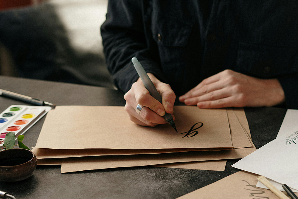 A calligrapher writing one letter of a word out to suggest the painting of a single initial of a writer to establish their authorship