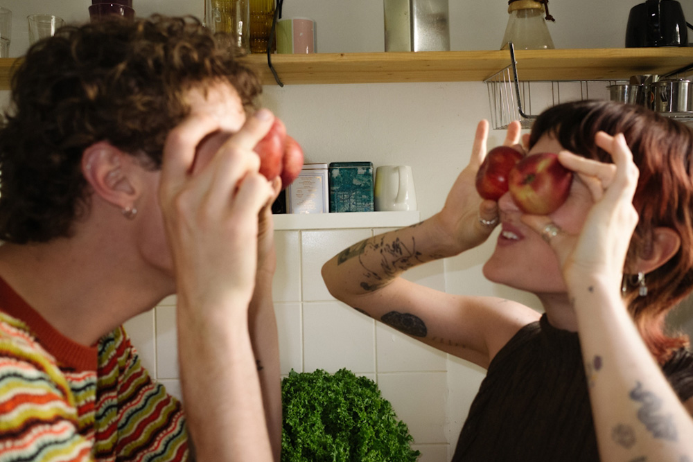 Two people making the same funny gesture with a pair of nectarines—mirrored humor is required in order for the jester to keep his head.