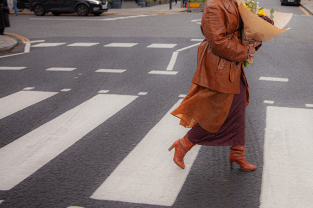 A woman on a crosswalk carrying flowers--signifying the single-lane road that one does not walk to traverse story structure.
