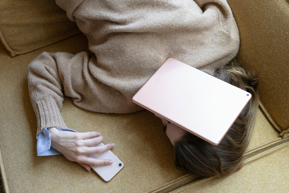 The burden of trying not to panic, visualized by a woman buried in her tablet and phone