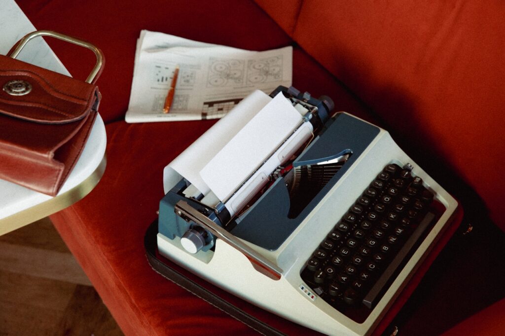 A neatly kept typewriter with a purse and a folded newspaper to suggest the organized nature required of a pantser type writer.