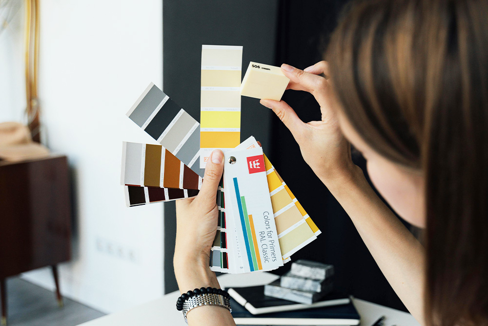 A designer holding up different color tiles to decide on how to design something, visual simile for book cover design schema and process