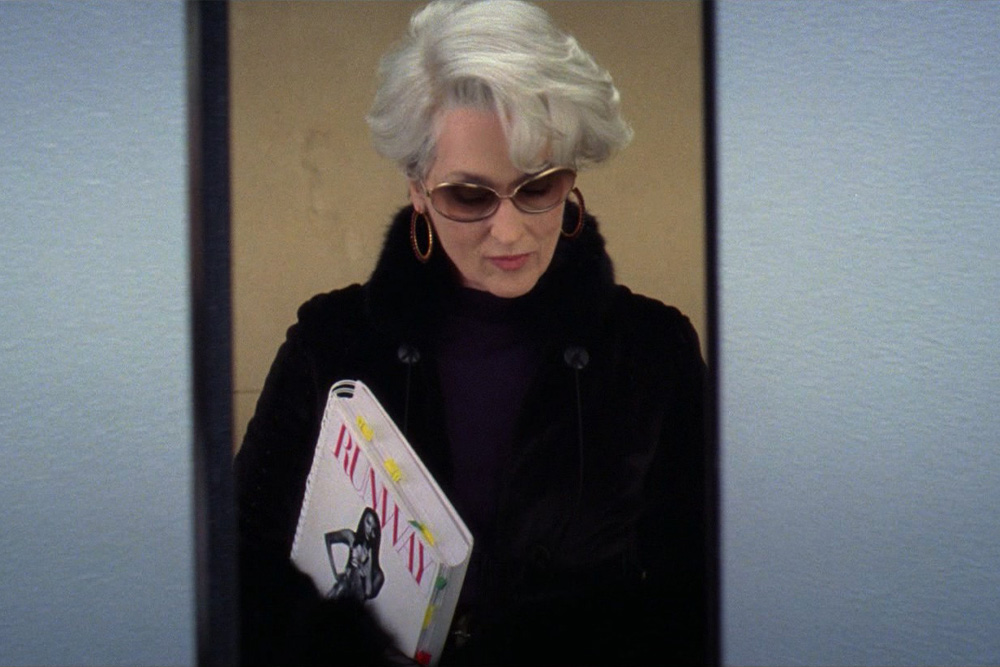 Miranda Priestly getting out of the elevator, an ominous and imposing figure who exudes power in the cool office setting of this film