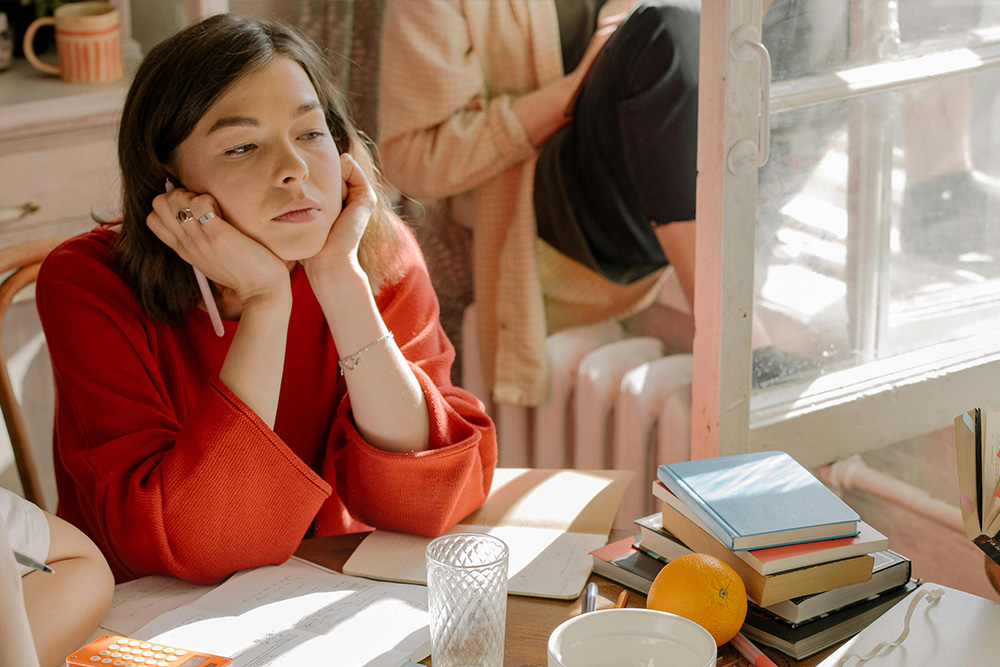 A woman in a red dress looking pensively to the corner of the frame to dramatize the difficulty of how to plan a novel