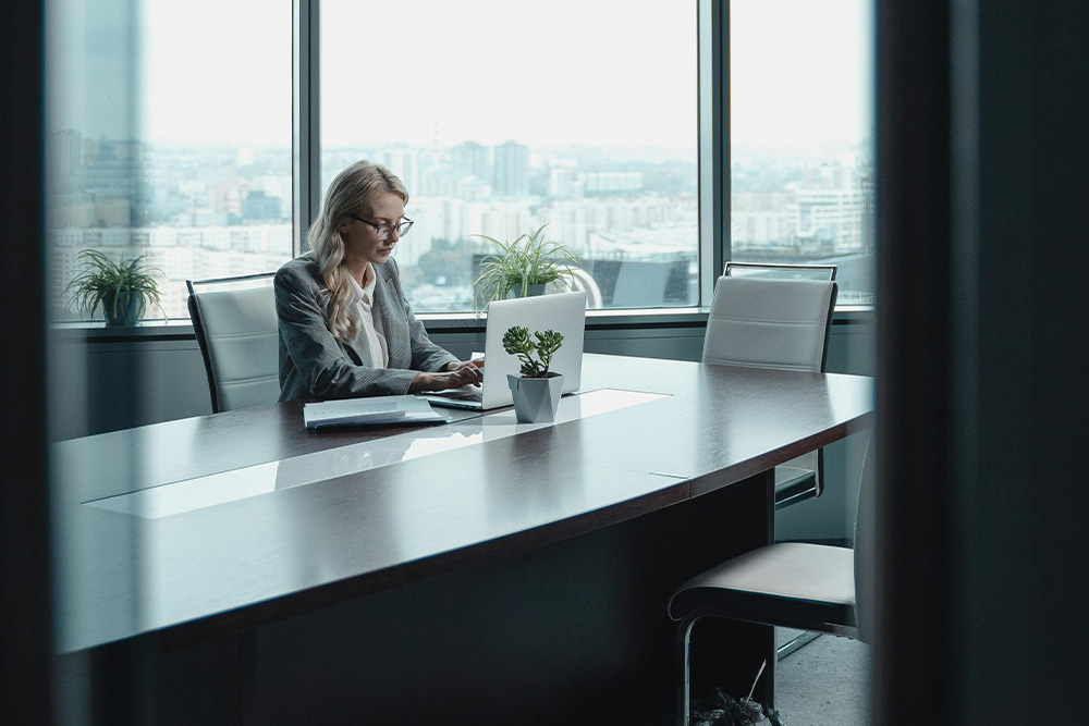 Literary agents are often one of the main factors in the success of your book. Pictured is a literary agent alone in a conference room working hard on getting your book published — cool corporate lighting