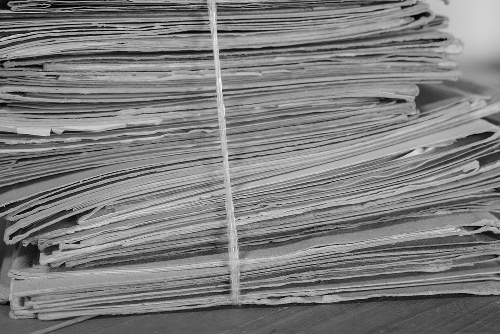 A stack of leather bindings atop a piece of wood to suggest a pile of rejected manuscripts piling up in a stack.