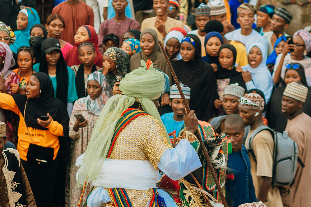 People in a village setting in cultural dress gathered for some kind of ceremony — visual cue to suggest what kind of histories, peoples, and cultures a writer can draw from to form an image of their world