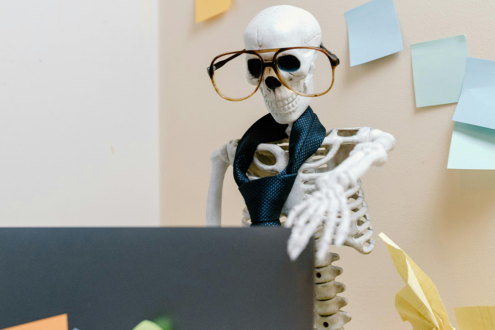 A skeleton typing on a computer to visualize the idea of an outline tracking a protagonist's experiences