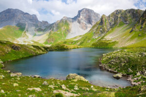Image of the caucasus mountains used to visualize the 10,000 hour rule and how it can be applied to you, above in the background are high mountain peaks certainly worth climbing but in the foreground is a lake that suggests a serenity and calm in the achievement of joy