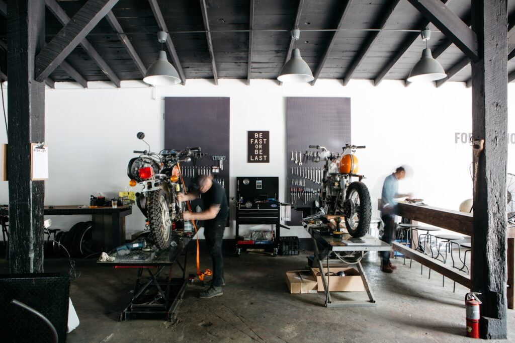 Mechanics working on motorcycles at a low shutter image capture to suggest the nature of continually working on a body of work to take on the proverbial road