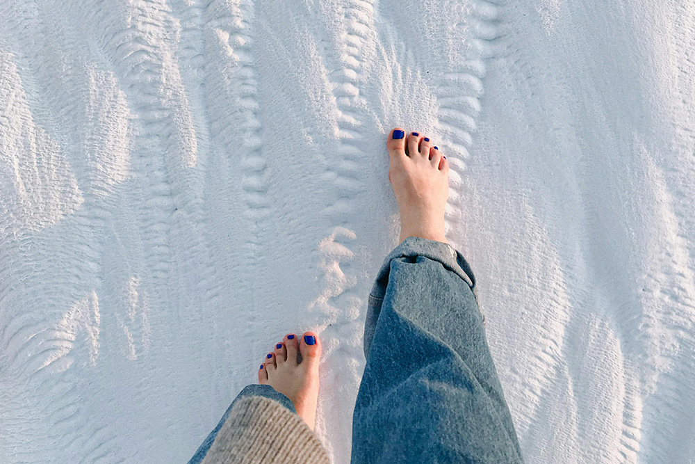 A woman with her bare feet traversing snow suggests sensory details and pain and softness in a character vs. nature conflict that creates an immediate visceral sensation in the viewer