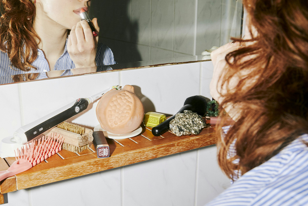 A woman applying makeup in a mirror to suggest coming of age as one of the common themes explored by writers