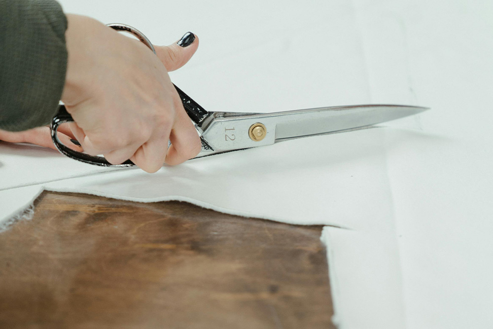 A pair of hands cut fabric messily to suggest cut corners when copy editing