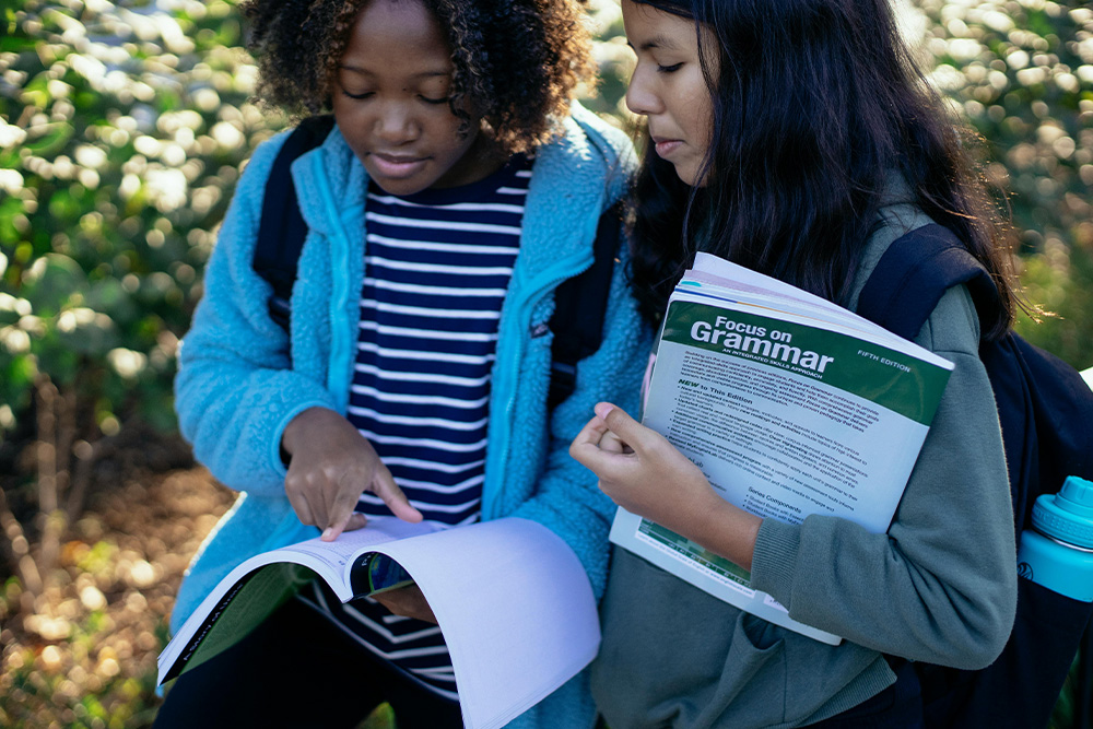 Two children carrying grammar textbooks that they may be carrying from childhood as they become working writers that are learning copy editing