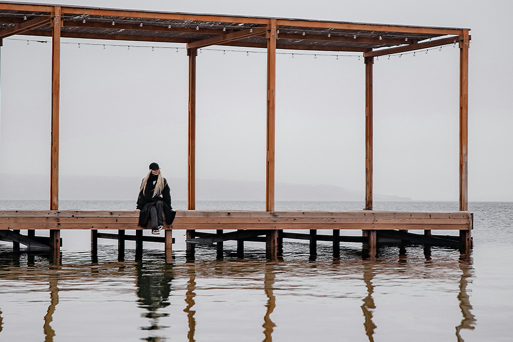 A serene scene of a person standing on a wooden dock over calm water, evoking solitude in how to self-publish a book