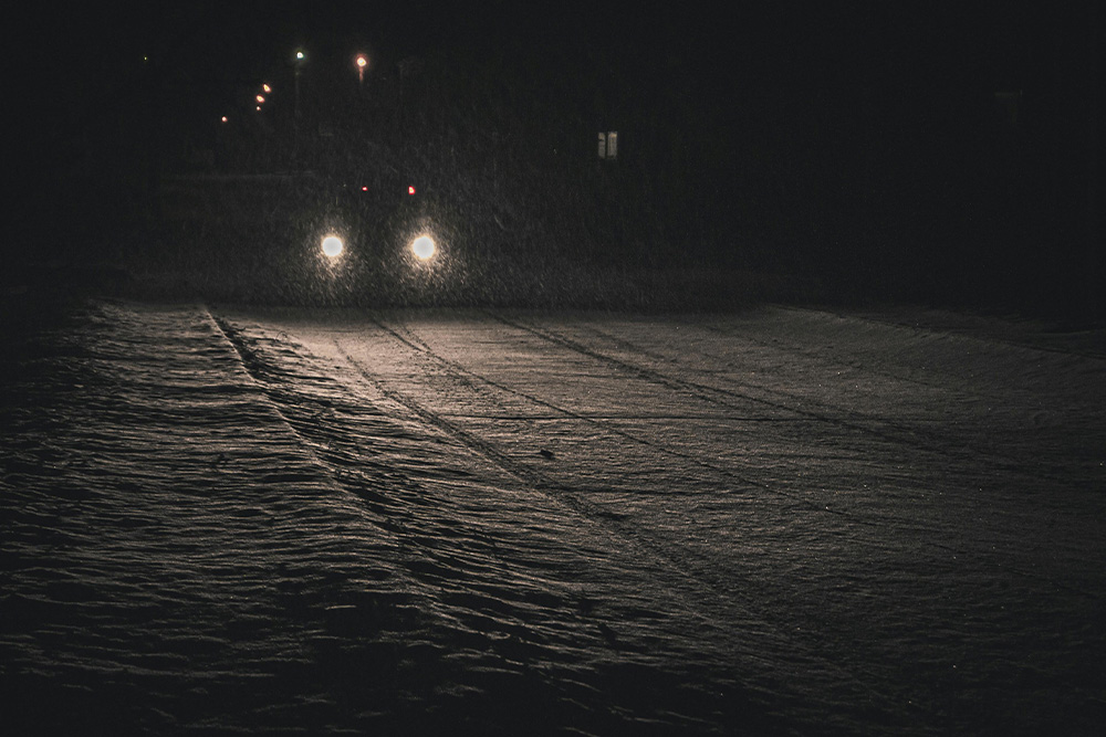 A car driving alone at night with only what is in front of its headlights illuminated to illustrate how the messy middle is contextually relevant to the writer's journey