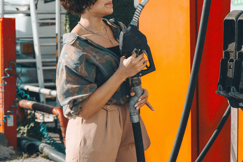 A woman pumping her gas preparing to navigate the messy middle of her story, a literal visualization of the idea that a story is only fueled by a good dilemma engine