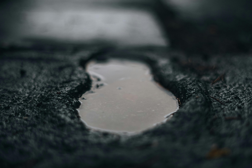 A puddle resembling a footprint on a dark, wet urban sidewalk suggests that by effectively proofreading authors can learn from the writers who have come before them to create compelling work