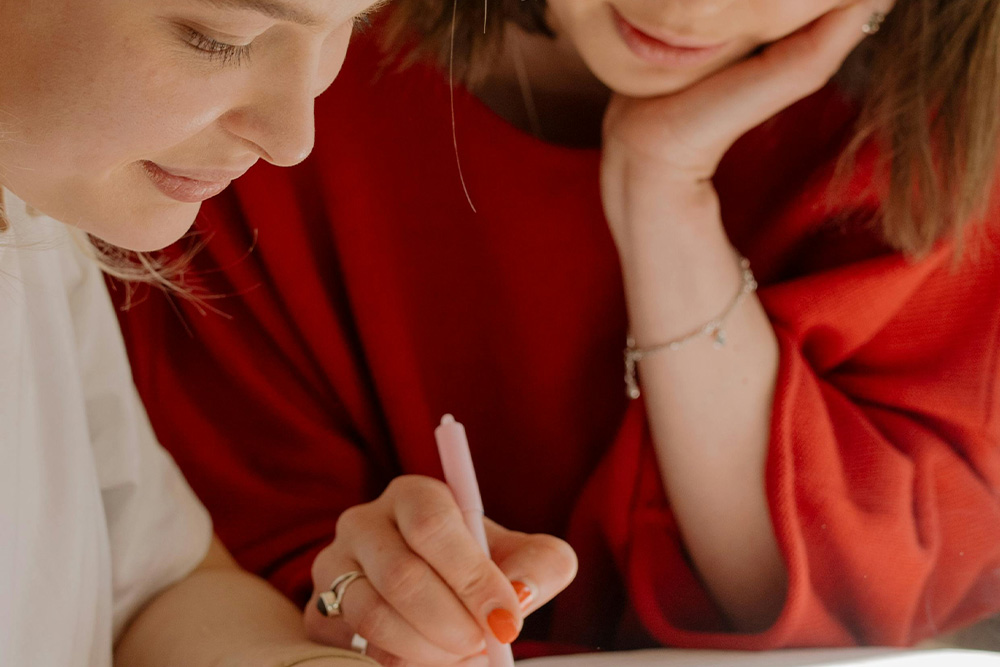 Getting comfortable with proofreading marks is to learn how the pros do it, visualized here by a woman in red with a pen marking up an author's page
