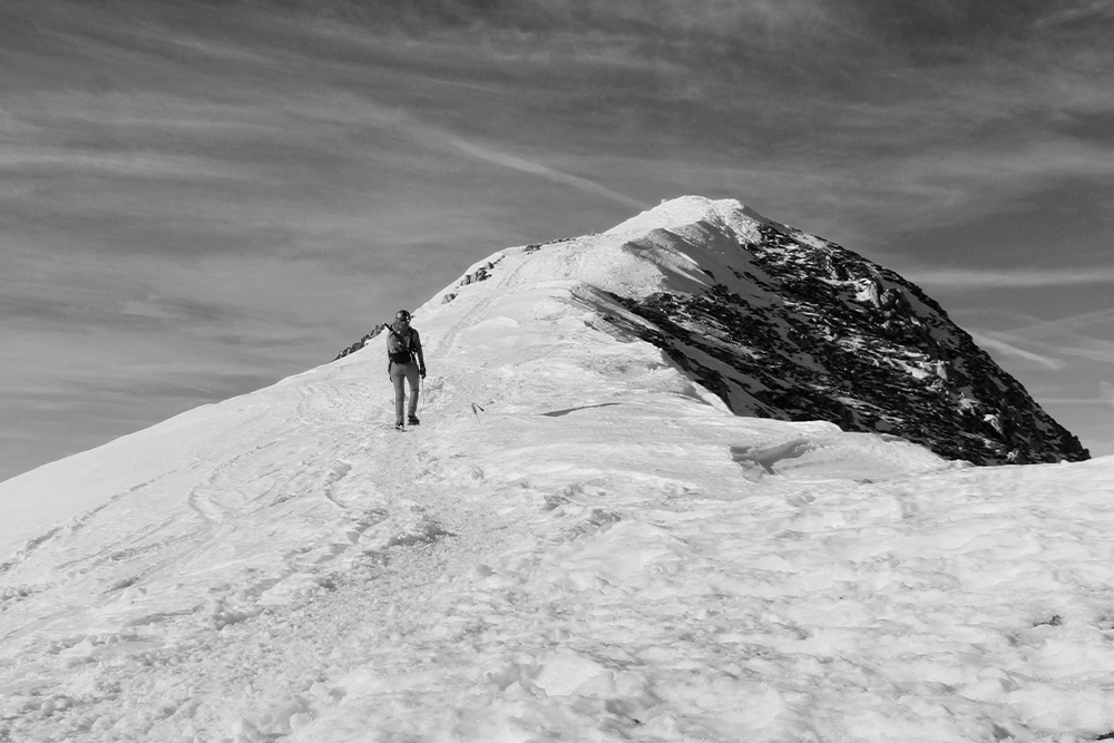 A man approaches the top of a white mountain peak to represent the protagonist making their way to a summit in Story structure