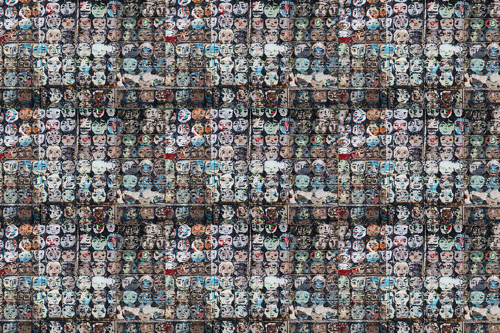 A crafty visualization of the hero with a thousand faces — a series of multicolored faces painted in a similar art style across a wall in different sizes and shapes to symbolize universal themes in story