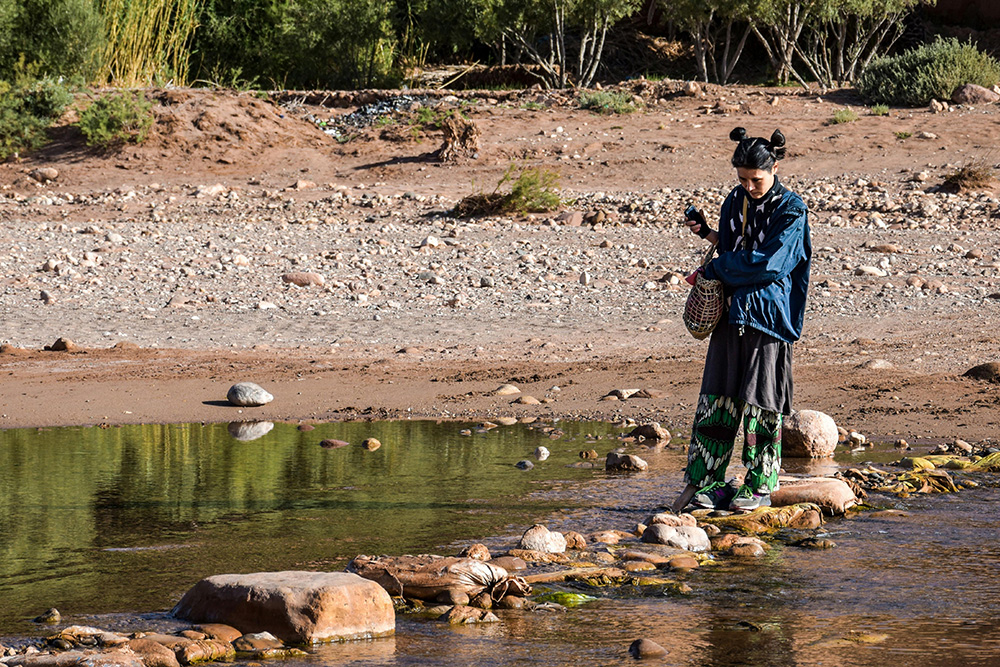 Someone walks carefully over rocks in a river to suggest the importance of not changing the original flow of a poem in how to quote a poem