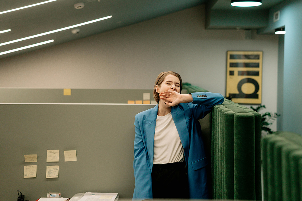 A woman yawns at her desk to suggest that passive voice misuse makes her very sleepy