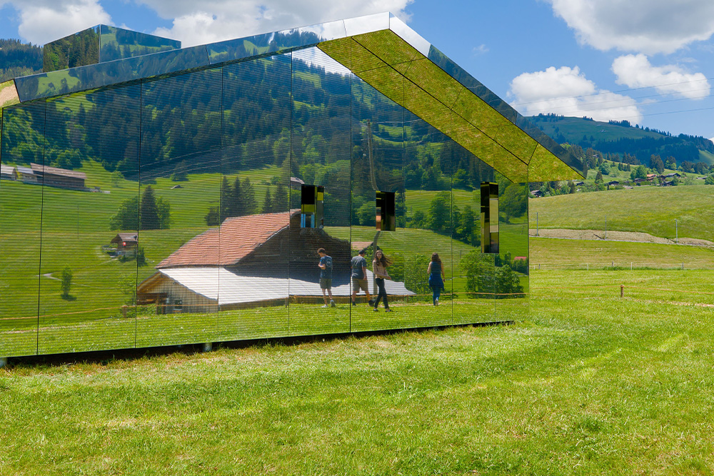 Characters walk by a glass house to suggest that the entire world is mirrored in the story of one's character ideas