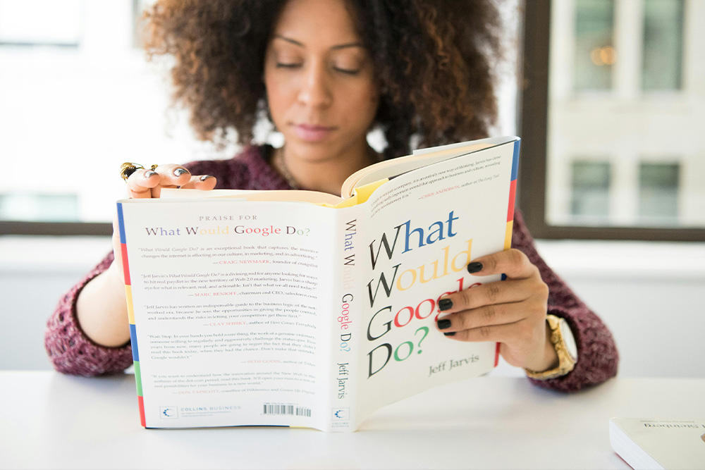 A woman reads What Would Google Do? to suggest an example in literature of character vs. technology conflict