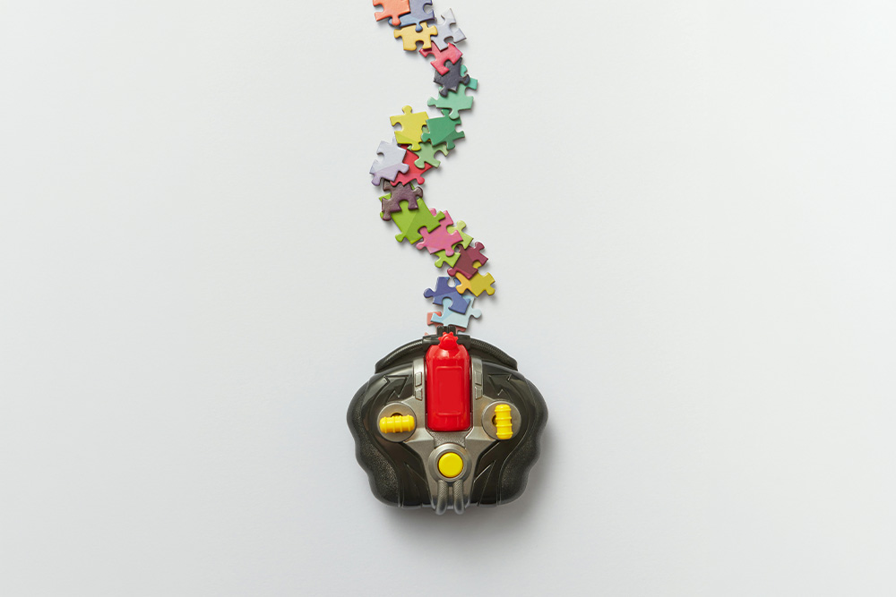 A controller below a series of puzzle pieces suggests that the controlling idea leads a writer through their narrative an an audience to the heart of the story's controller