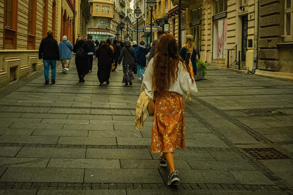 A woman walks her own path behind the crowd to suggest the creator archetype is a powerful character that beats to their own drum