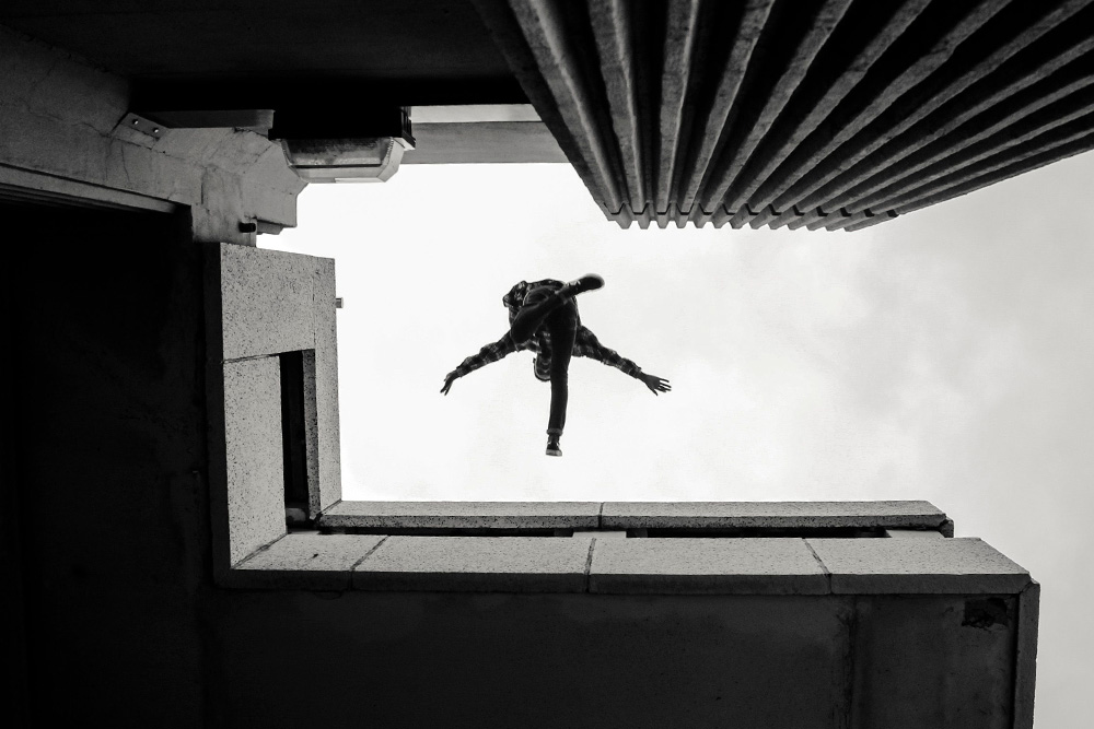 A man jumps over a building and looks down at the camera as he does it to suggest the traps writers fall into when selecting descriptive adjectives