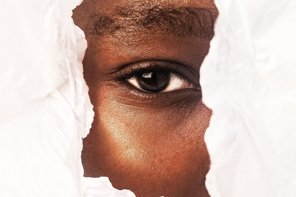 A woman peers through a piece of torn paper to suggest what descriptive adjectives reveal about character