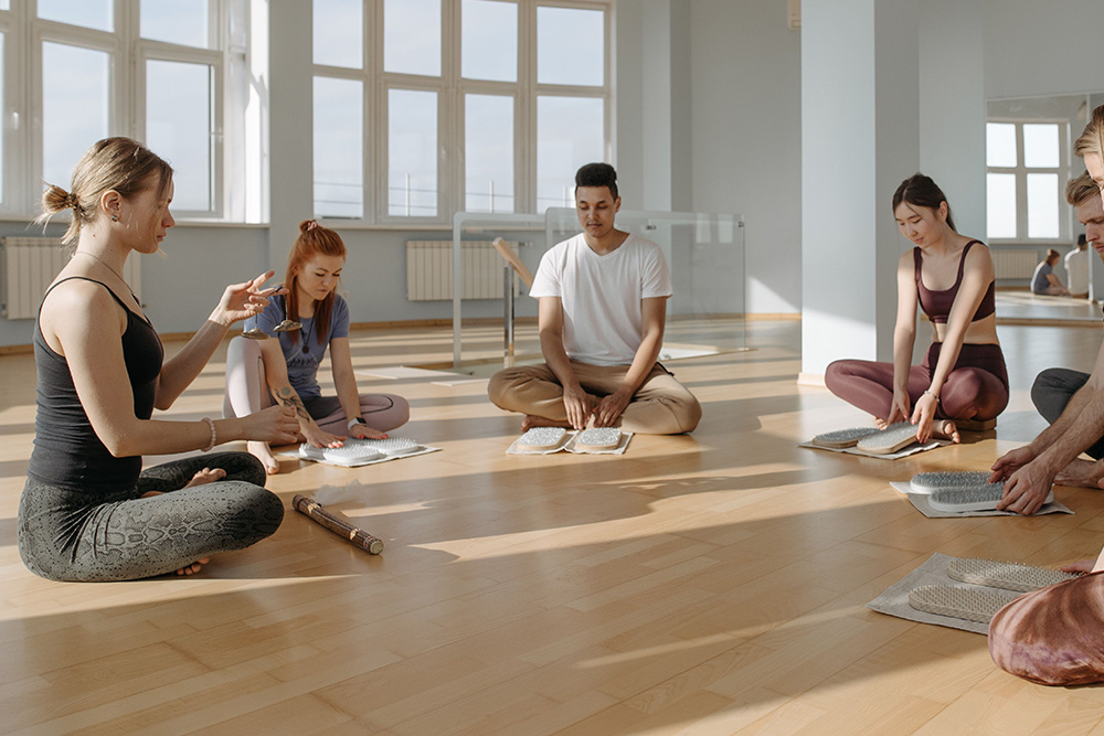 A yoga instructor has their hands outstretched while explaining a concept to students to suggest a few things to keep in mind about descriptive adjectives before putting them into practice