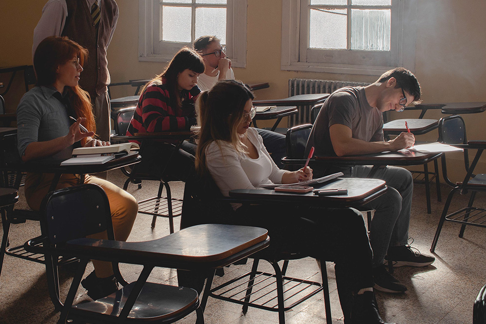 A diverse classroom of people all sit around taking notes to suggest that different kinds of writers may have certain notes to keep in mind