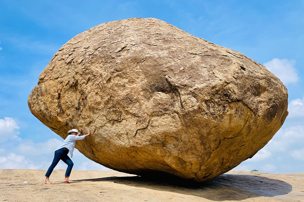 A woman tries to push a boulder with a smile on her face to suggest that story should be focused on before you get wrapped up in the weeds