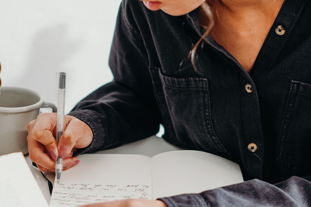 a woman with a coffee cup and a half filled page as a visual for how to start a novel