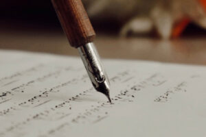 A pen touches down to paper neatly to suggest how to write a query letter