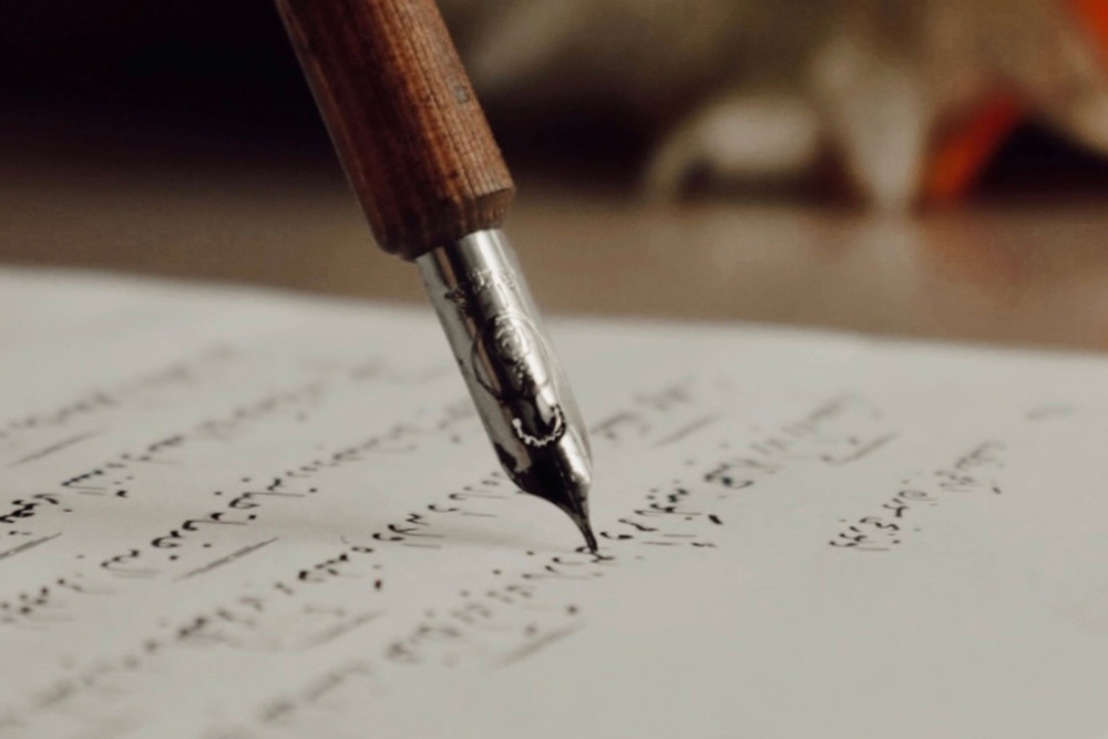 A pen touches down to paper neatly to suggest how to write a query letter