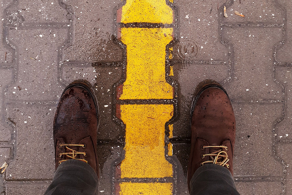 A person standing behind a yellow line that tracks off-frame in the rain suggests how you can get back onto the road when you have lost the plot in your story