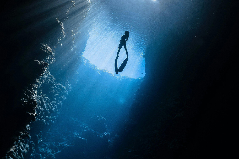 A woman dives deep into a reef to suggest how prompts can help you access deep truths with memoir writing prompts
