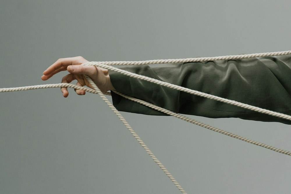 Memoir writing prompts are represented abstractly as a form of structure that pull you more than you pull them by four ropes wrapped around an arm and a part of the thread reaching off screen