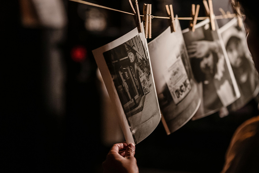 Pictures hang in a dark room to signify how memoir writing prompts are ideas that are already developing you as a photograph does